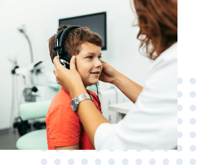 Audiologist preforming a pediatric hearing test on a young boy